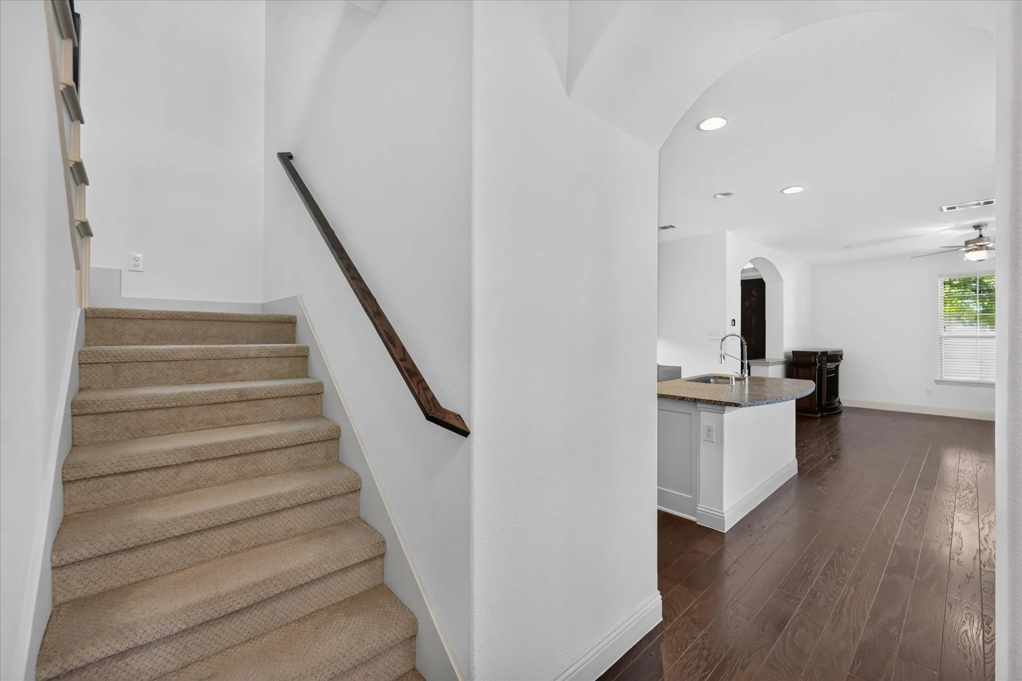 Carpeted staircase with dark wood handrail