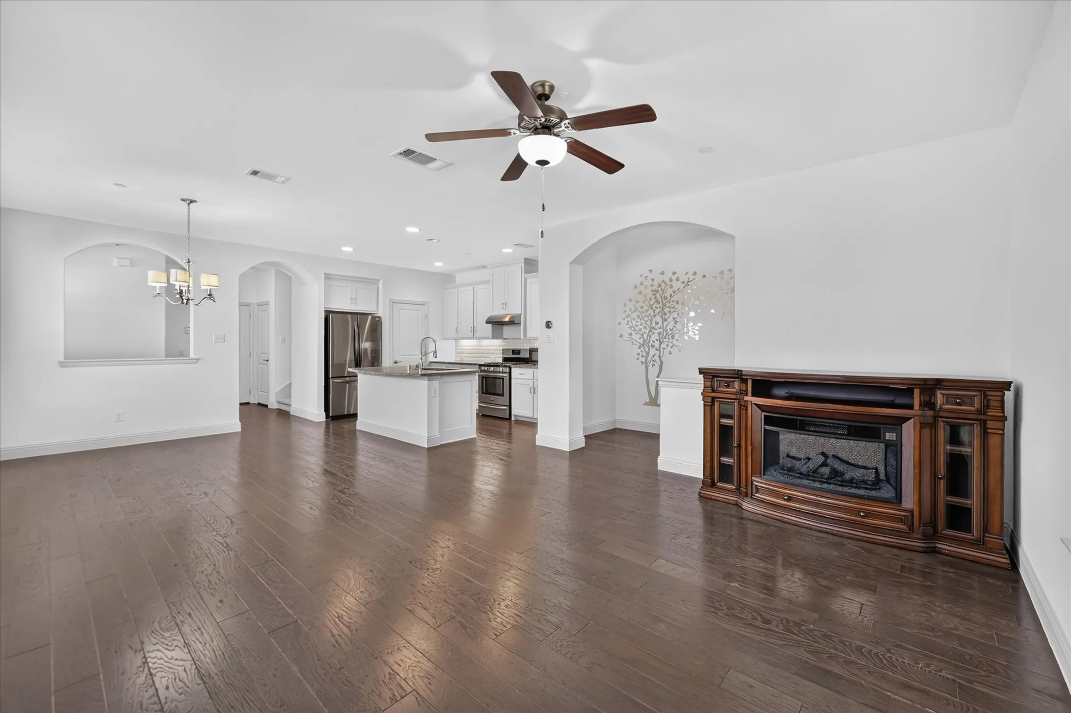 Spacious open-concept layout with wood-finish flooring, a built-in fireplace, and an integrated kitchen with stainless steel appliances