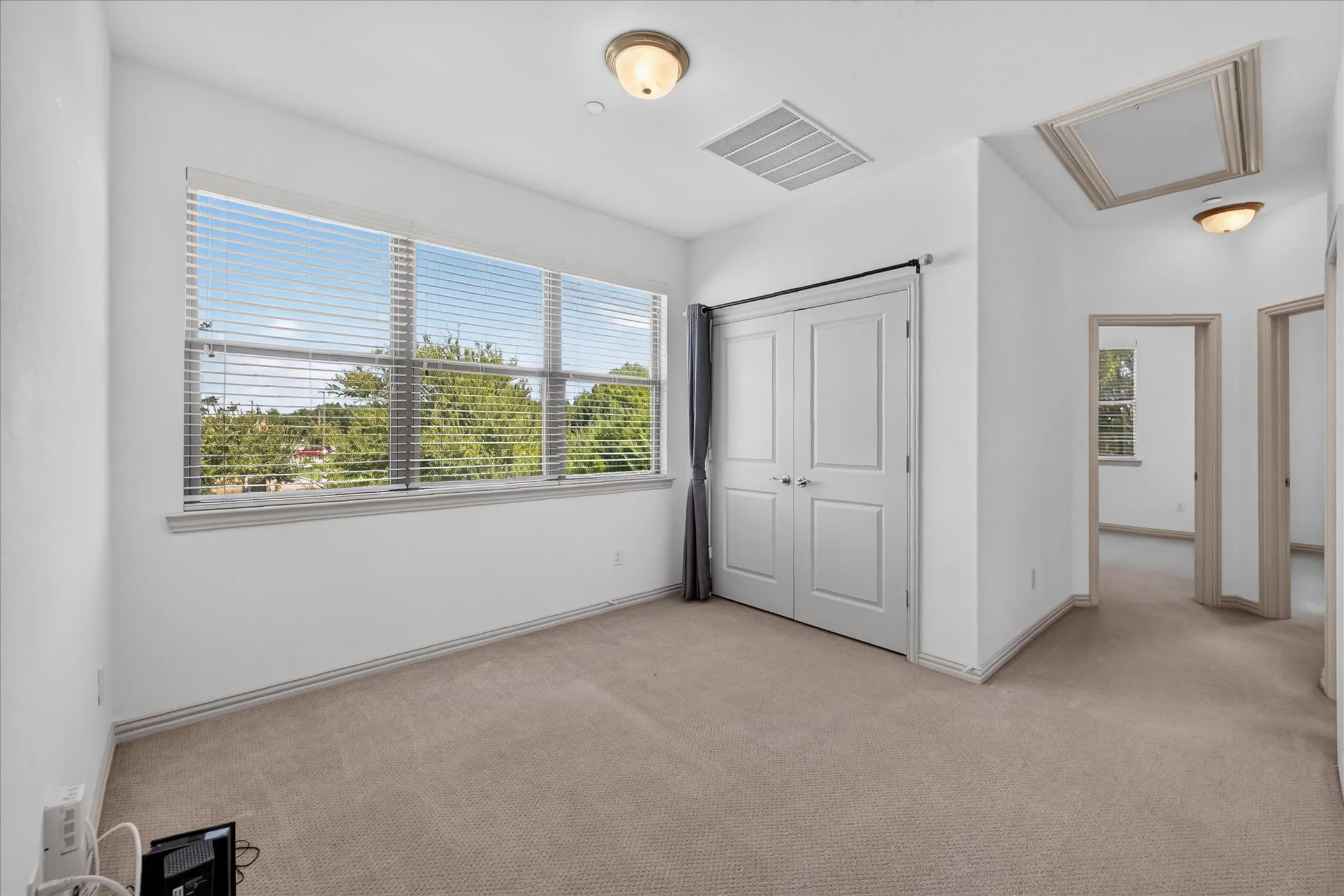 Neutral tone carpet flooring, white walls, double panel closet doors, and recessed lighting