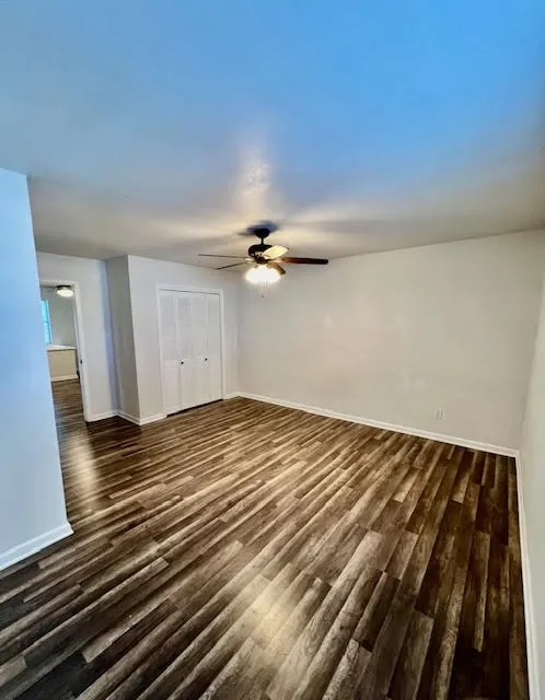 Wood-finish flooring throughout, bright white walls, and a ceiling fan with integrated lighting