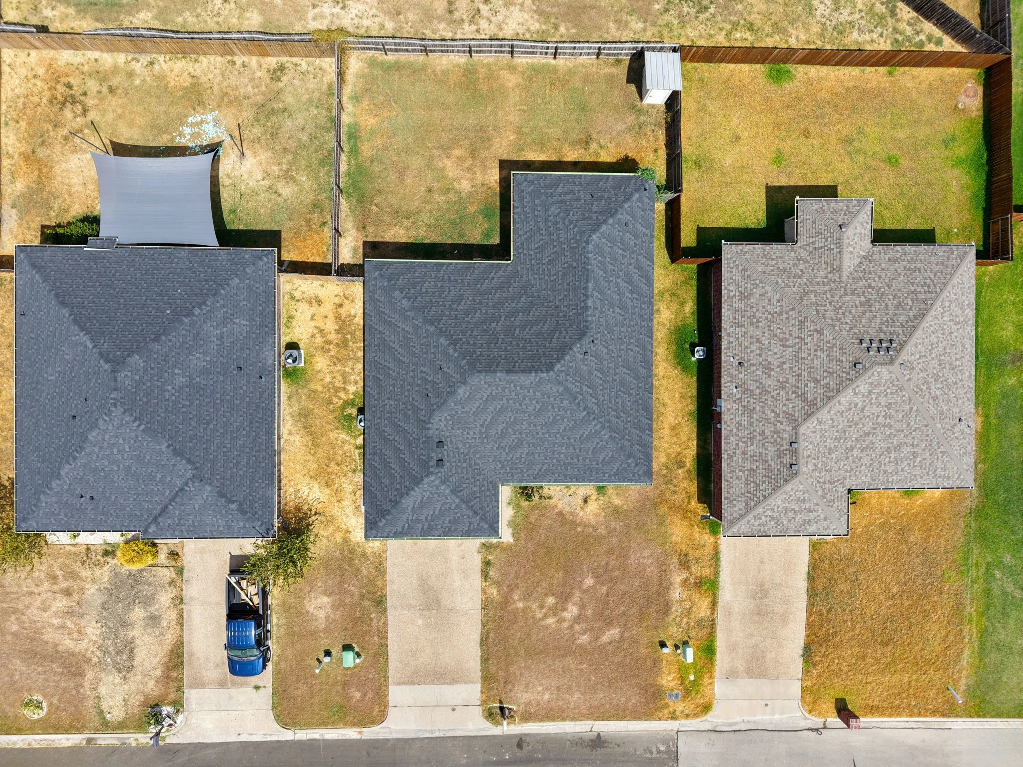 Asphalt shingle roofing, concrete driveway, fenced perimeter, and expansive yard