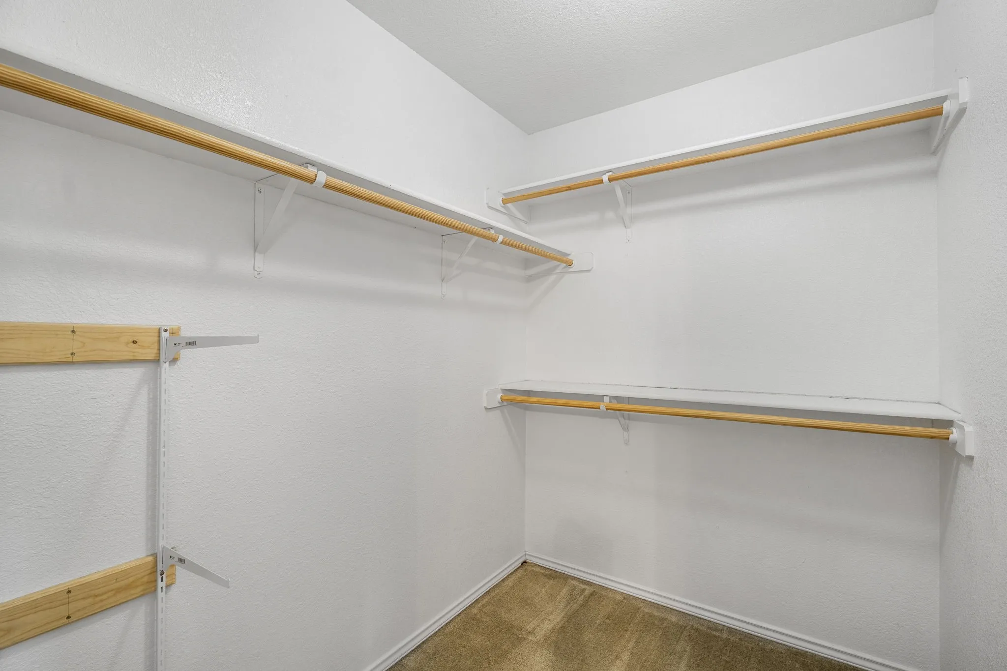 Walk-in closet with multiple levels of wood-finish shelving and hanging rods