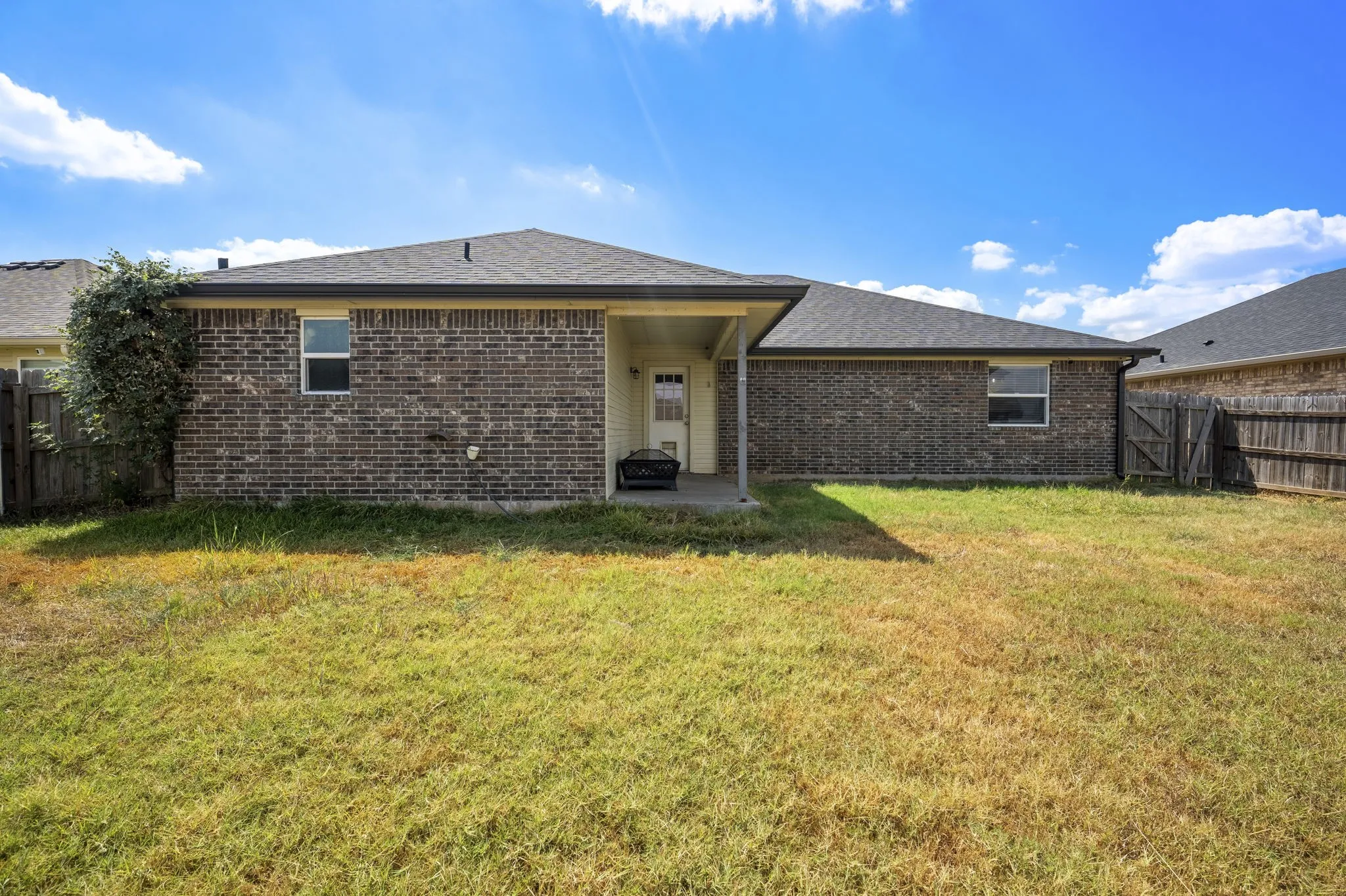 Brick exterior with a covered patio and a privacy fence