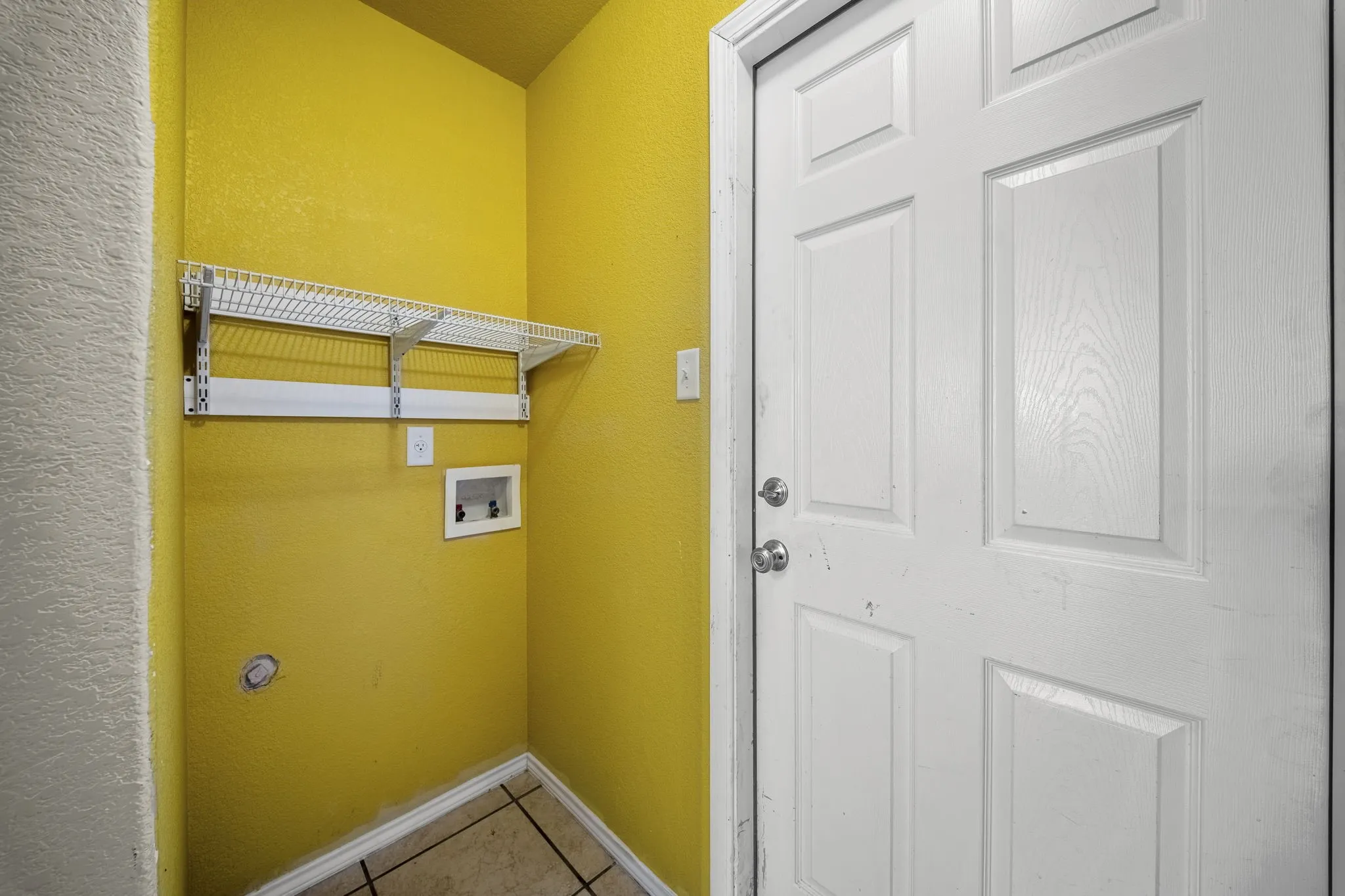 Utility area featuring a wire shelf system, appliance hookups, and tiled flooring