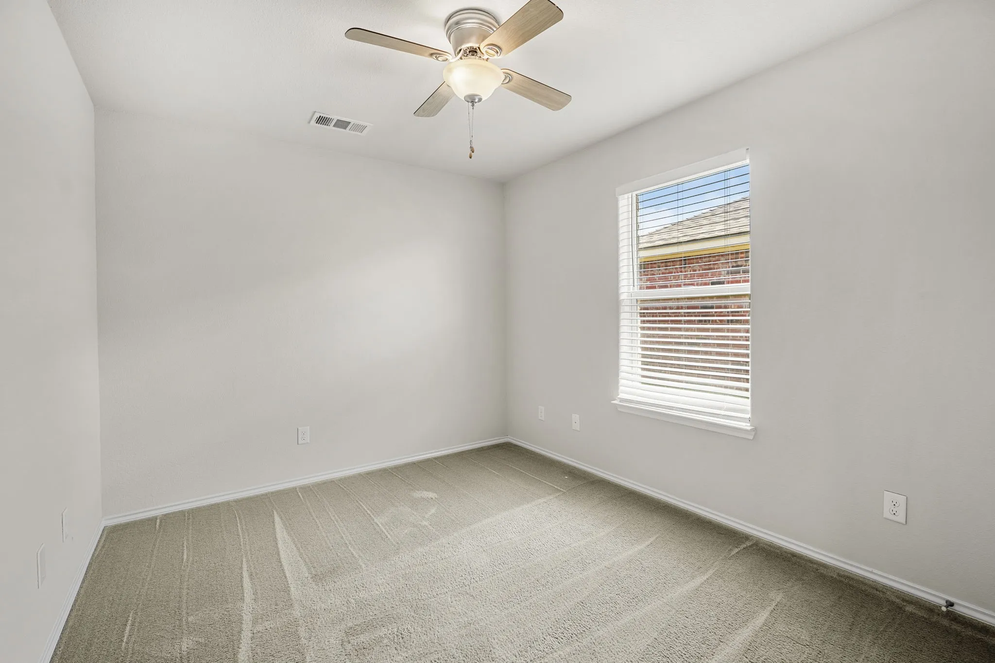 Recessed window with white blinds, neutral wall paint, ceiling fan with light fixture, and carpet flooring