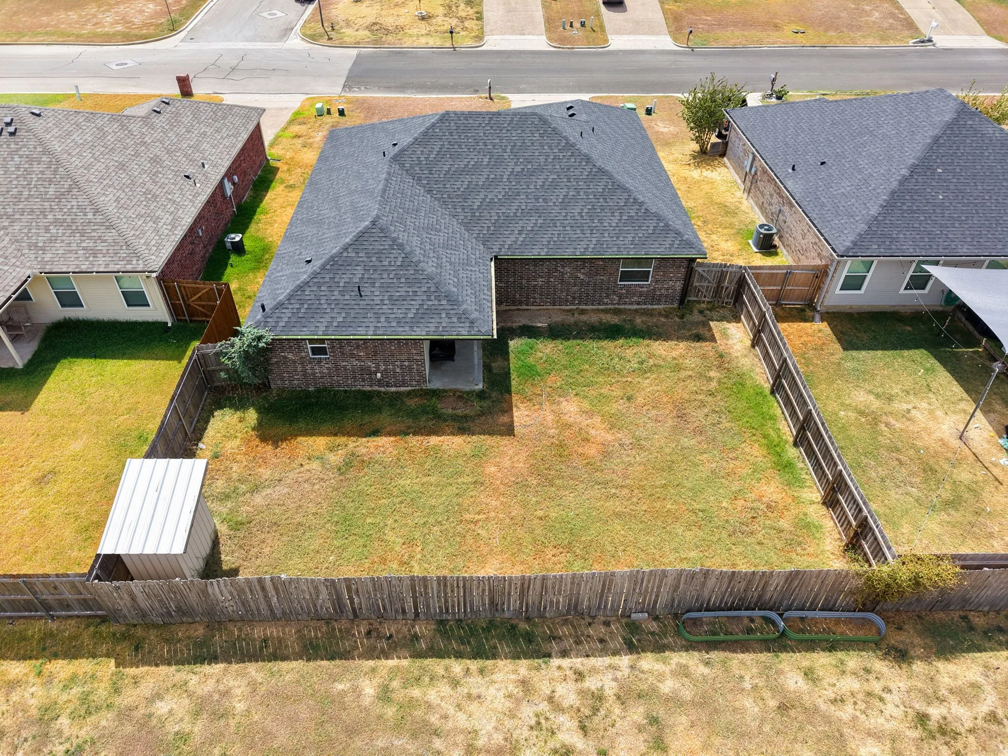 Fenced backyard with a storage shed and a covered patio area