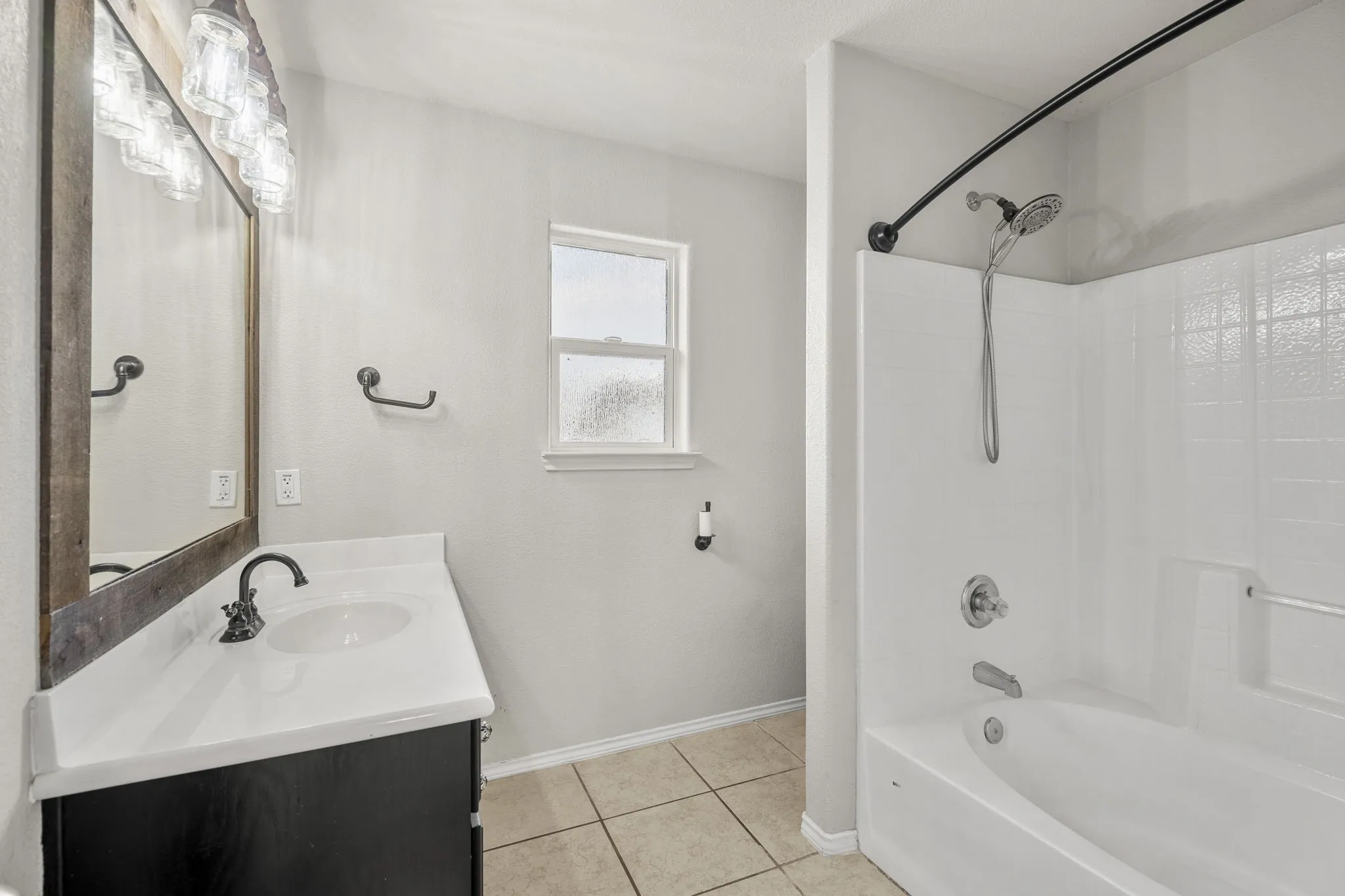 Bathroom featuring a single vanity with dark cabinetry, a white countertop, and a basin sink with a dark-finished faucet