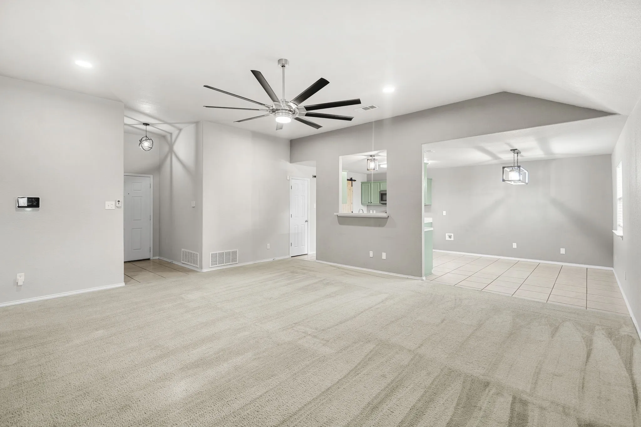 Carpeted living area with vaulted ceilings, recessed lighting, and a contemporary ceiling fan