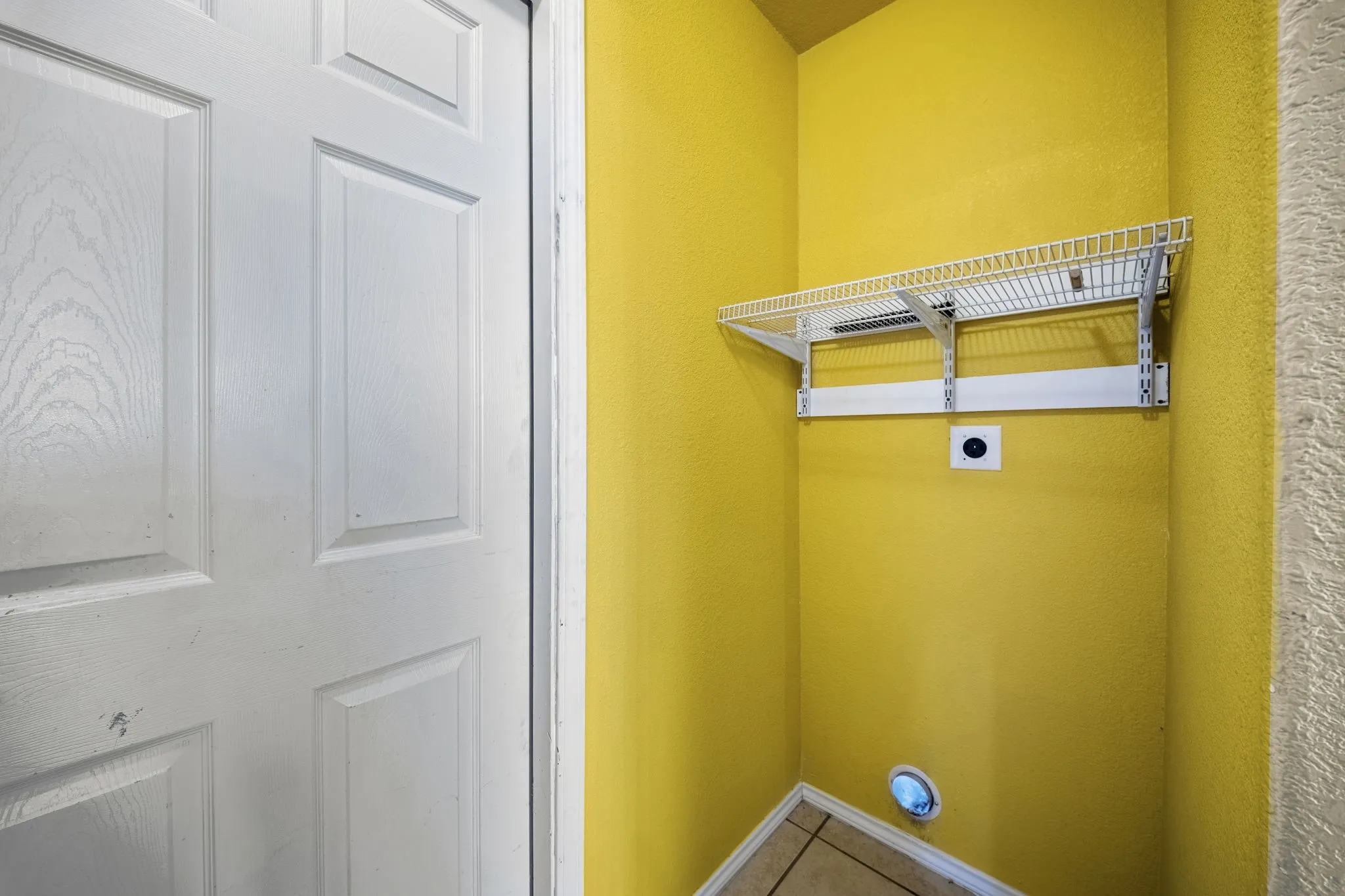 Built-in wire shelving with wall-mounted brackets, tile flooring, and utility hookups