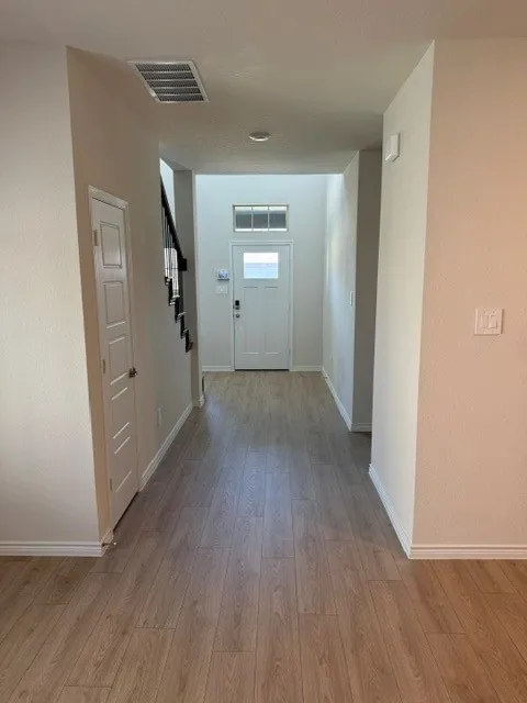 Entryway featuring wood-finish flooring, a white paneled door, and a staircase with black railings