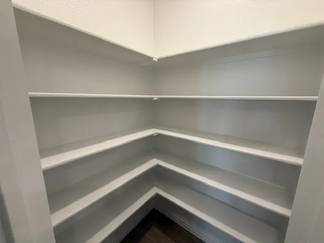 Built-in shelving with multiple storage levels, crisp white finish, and wood-finish flooring
