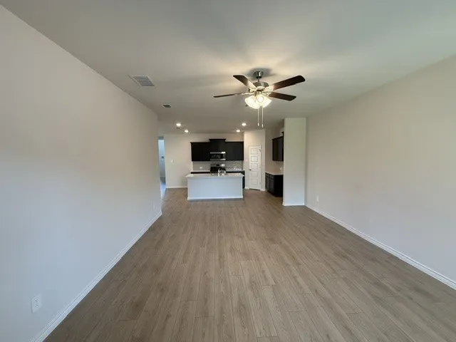 Wood-finish flooring throughout, with a ceiling fan in the foreground