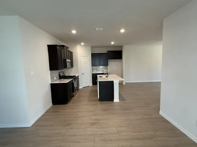 Spacious kitchen featuring dark wood cabinetry, a light-toned countertop, and stainless steel appliances
