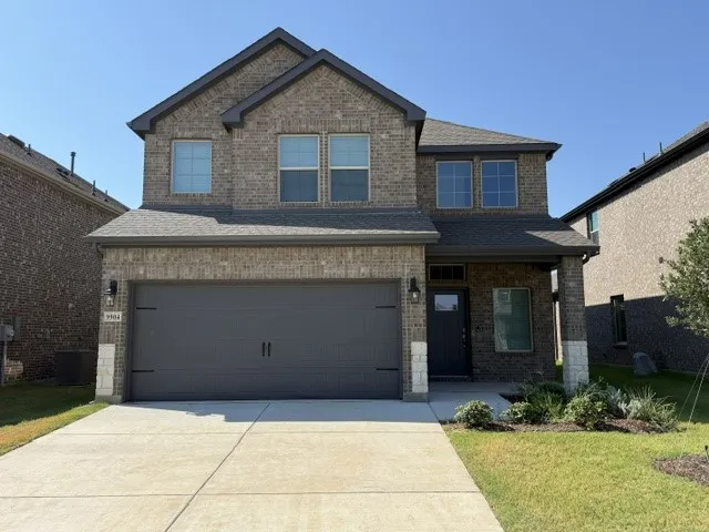 Two-story brick exterior with an attached two-car garage, covered entry, and landscaped front yard