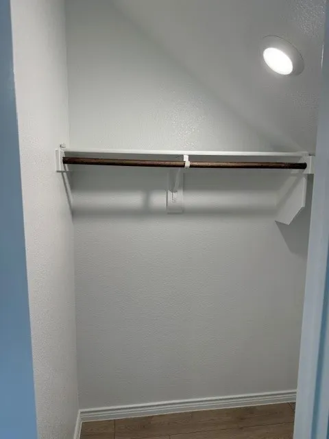 Built-in clothes rod, recessed ceiling lighting, wood-finish flooring, and crown molding