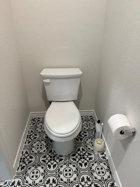 White toilet with a patterned black and white floor tile