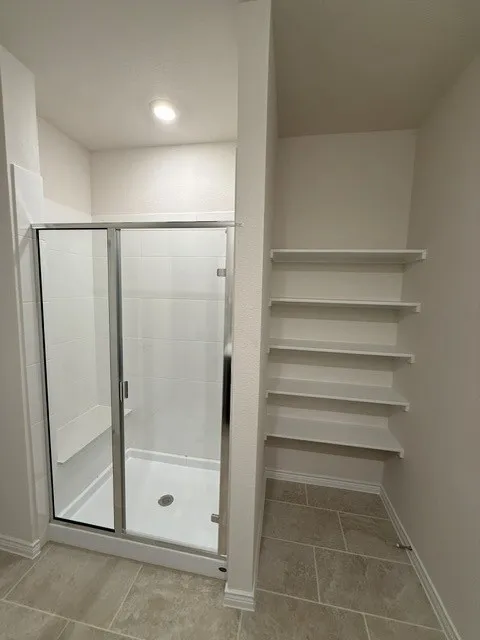 Shower enclosure with clear glass door, built-in bench, and tile-finish flooring