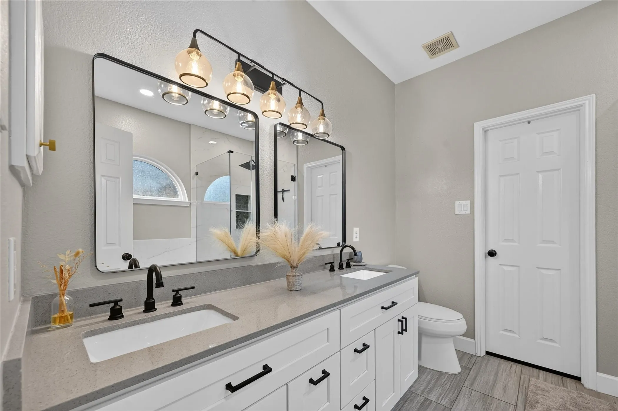 Remodeled primary bath with new cabinets, quartz counters, upgraded mirrors and lighting.