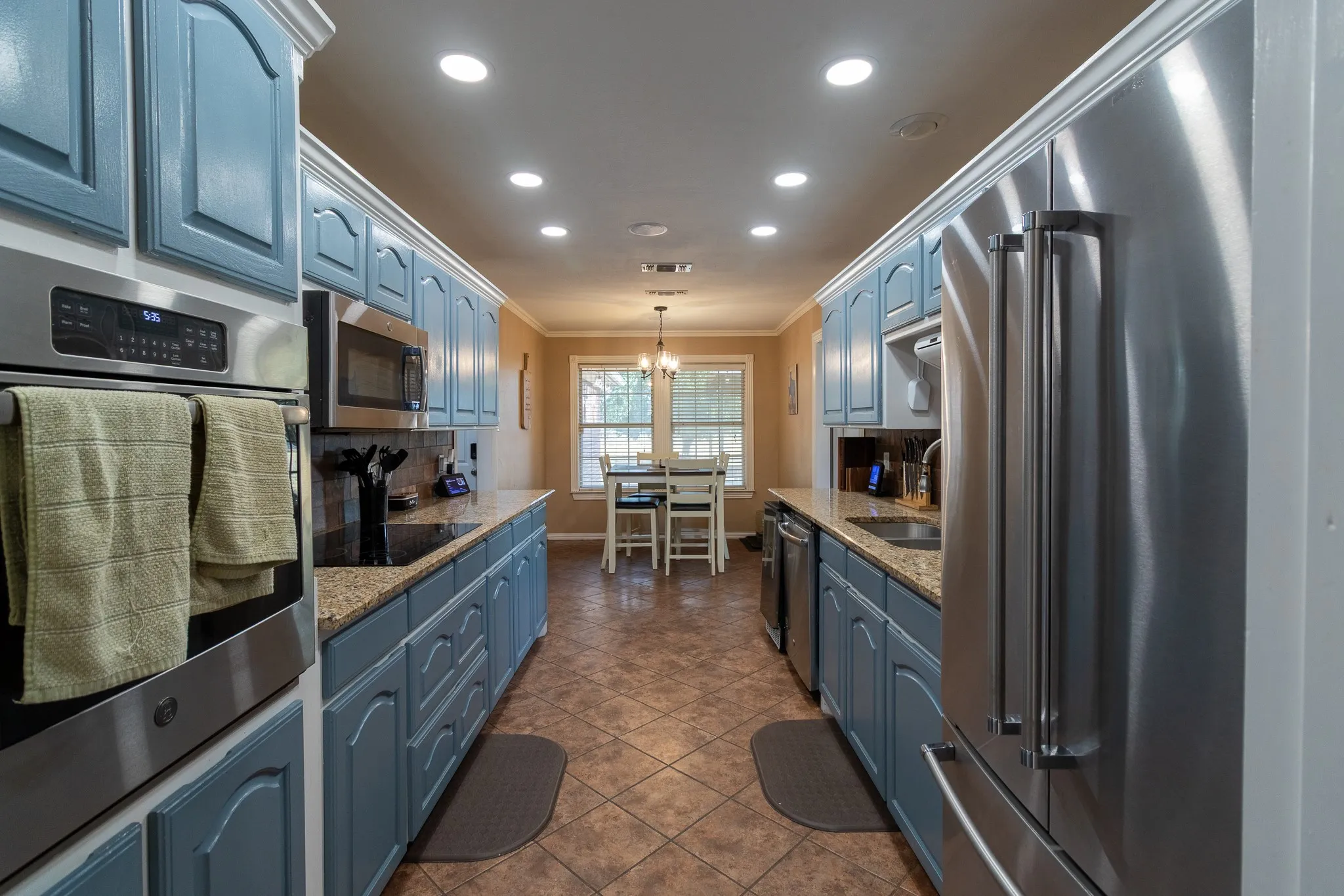 Kitchen with recessed lighting, stainless steel appliances, blue cabinetry, granite countertops, and tiled flooring