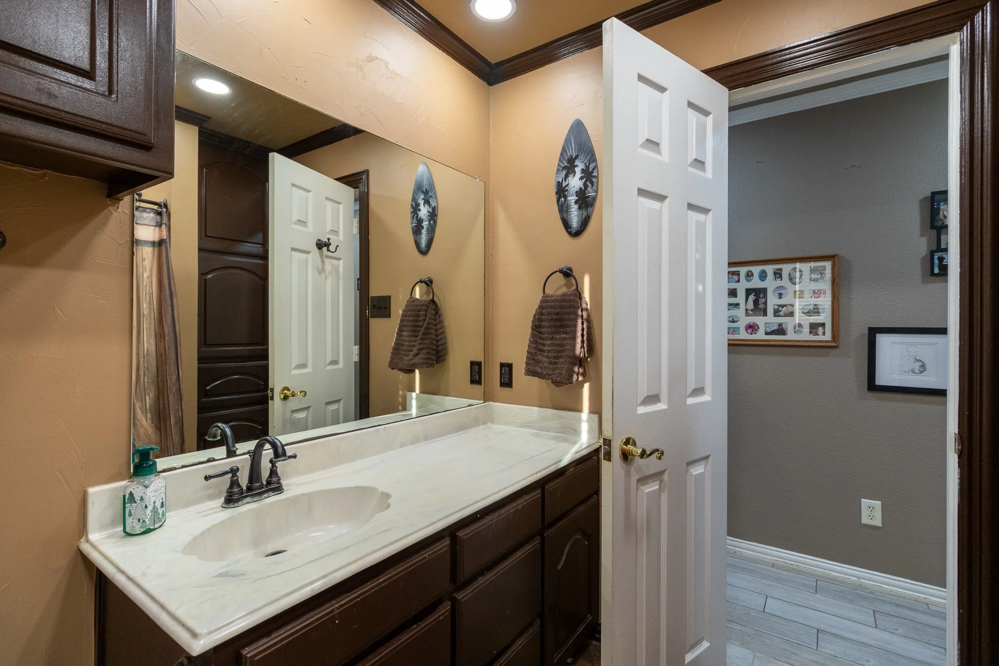 Single vanity with an integrated sink, dark wood-finish cabinetry, and a large wall-mounted mirror