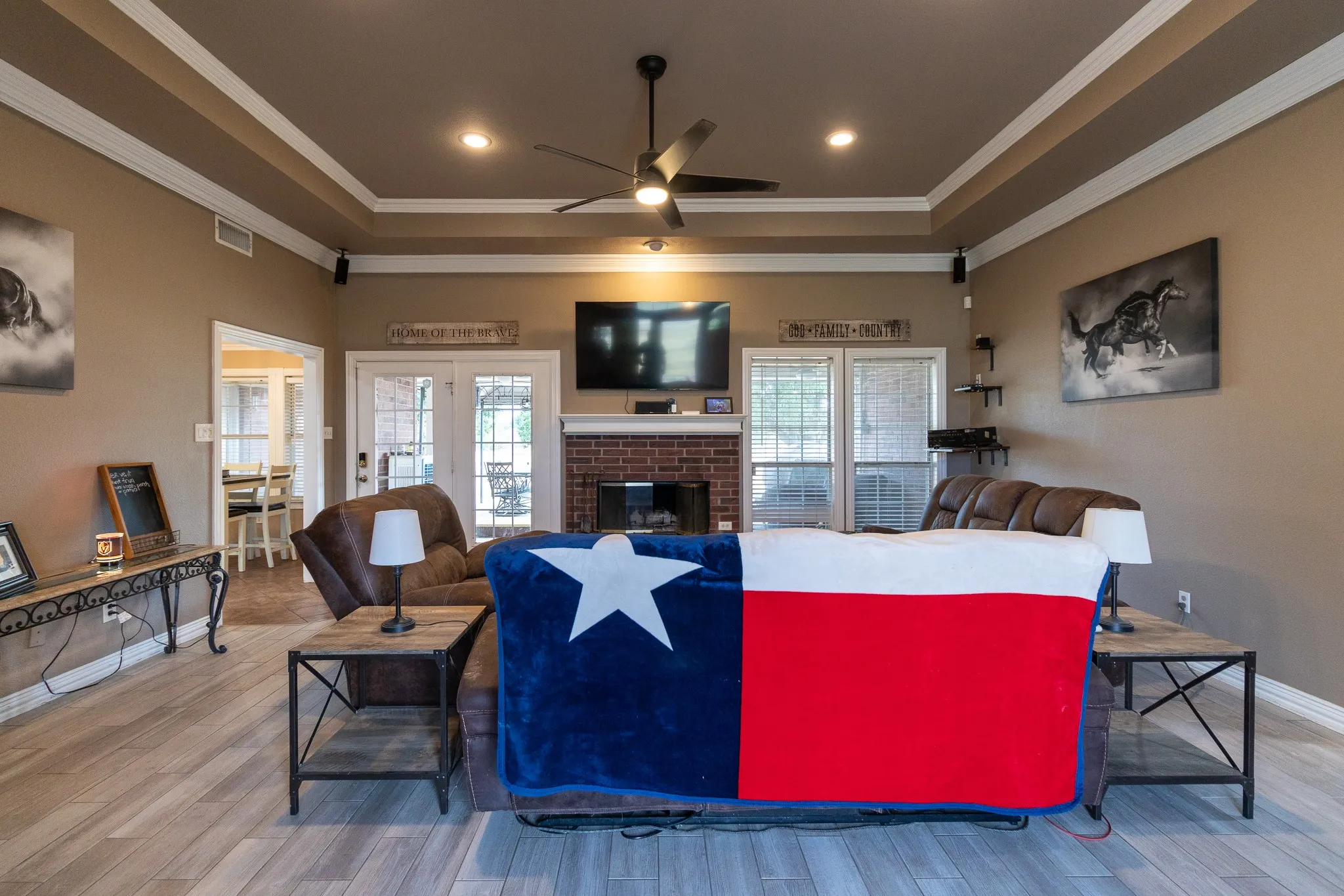 Tray ceiling with recessed lighting, ceiling fan, wood-finish flooring, brick fireplace, and French doors