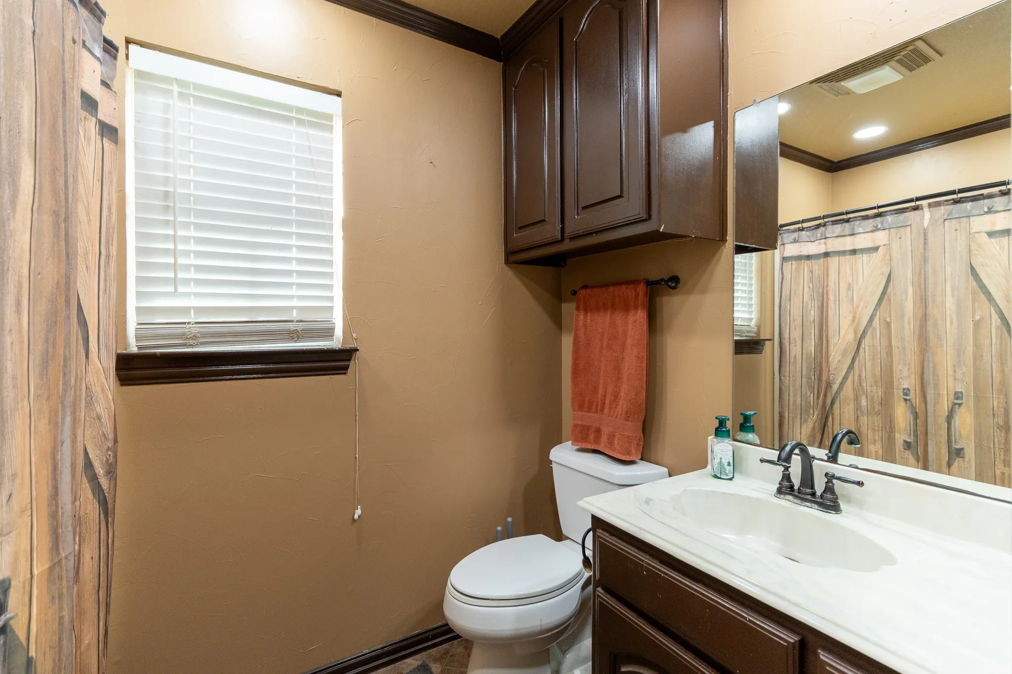 Vanity with integrated sink and dark bronze faucet, dark wood-finish cabinetry, and full-width mirror