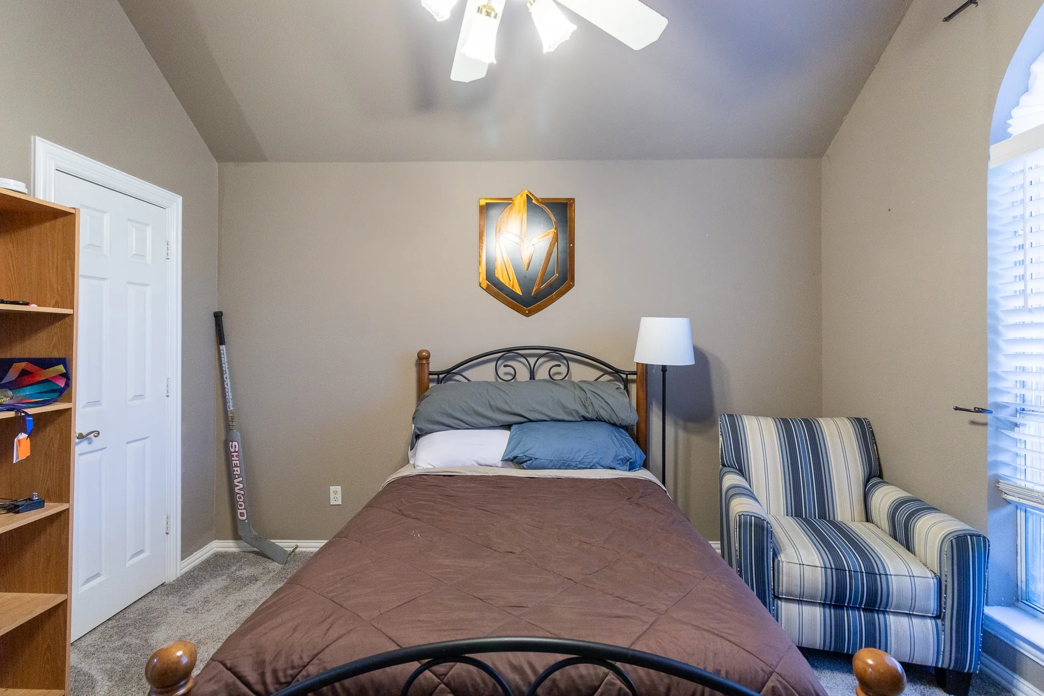 Arched window with blinds, ceiling fan, carpeted flooring, and a white paneled door
