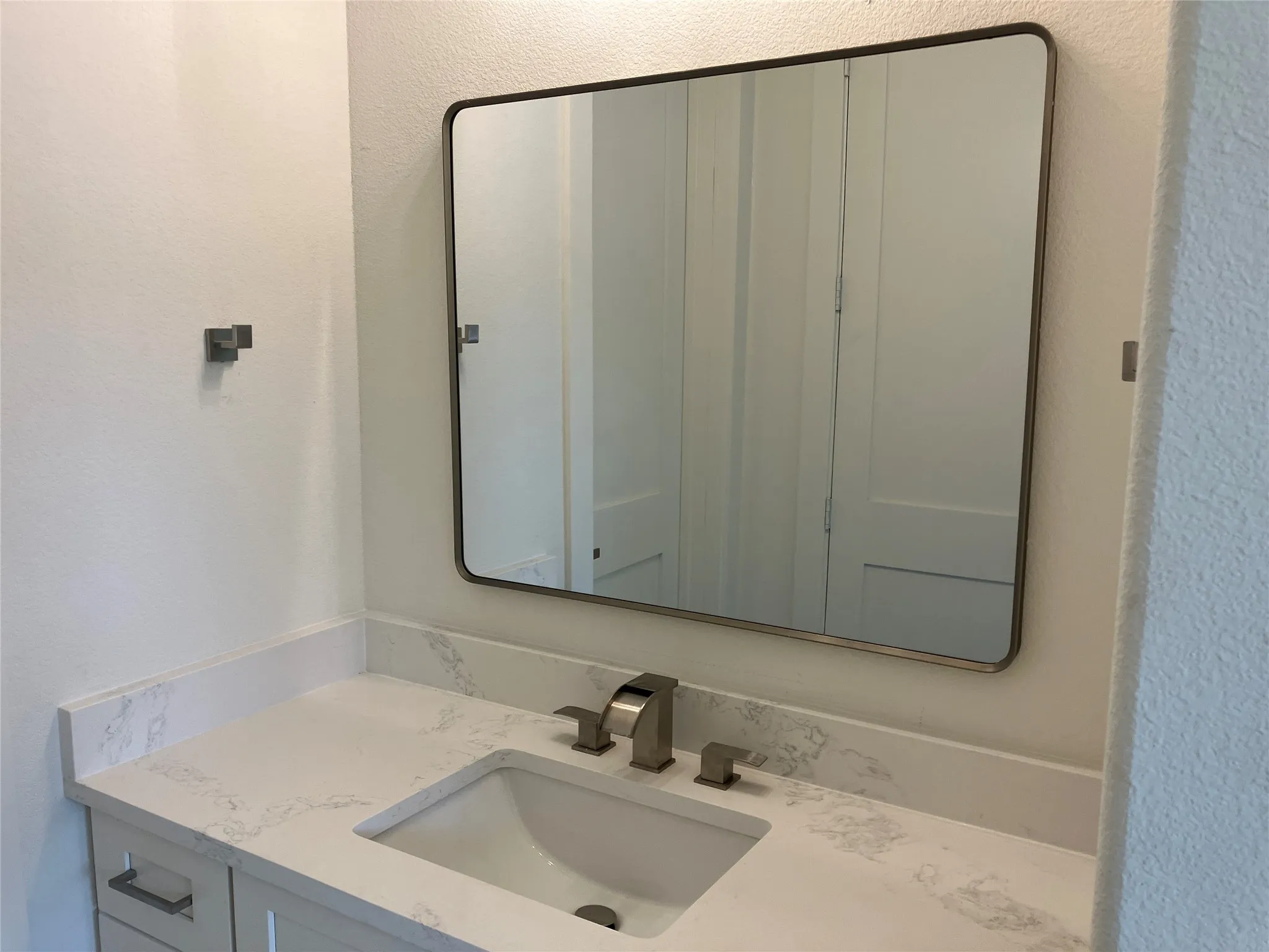 White vanity with shaker-style cabinetry, a rectangular undermount sink, and a brushed nickel faucet