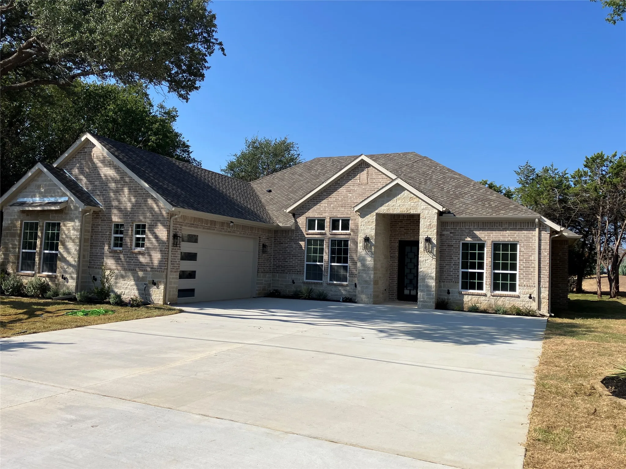 Brick and stone exterior with a concrete driveway, multi-pane windows, and a modern garage door