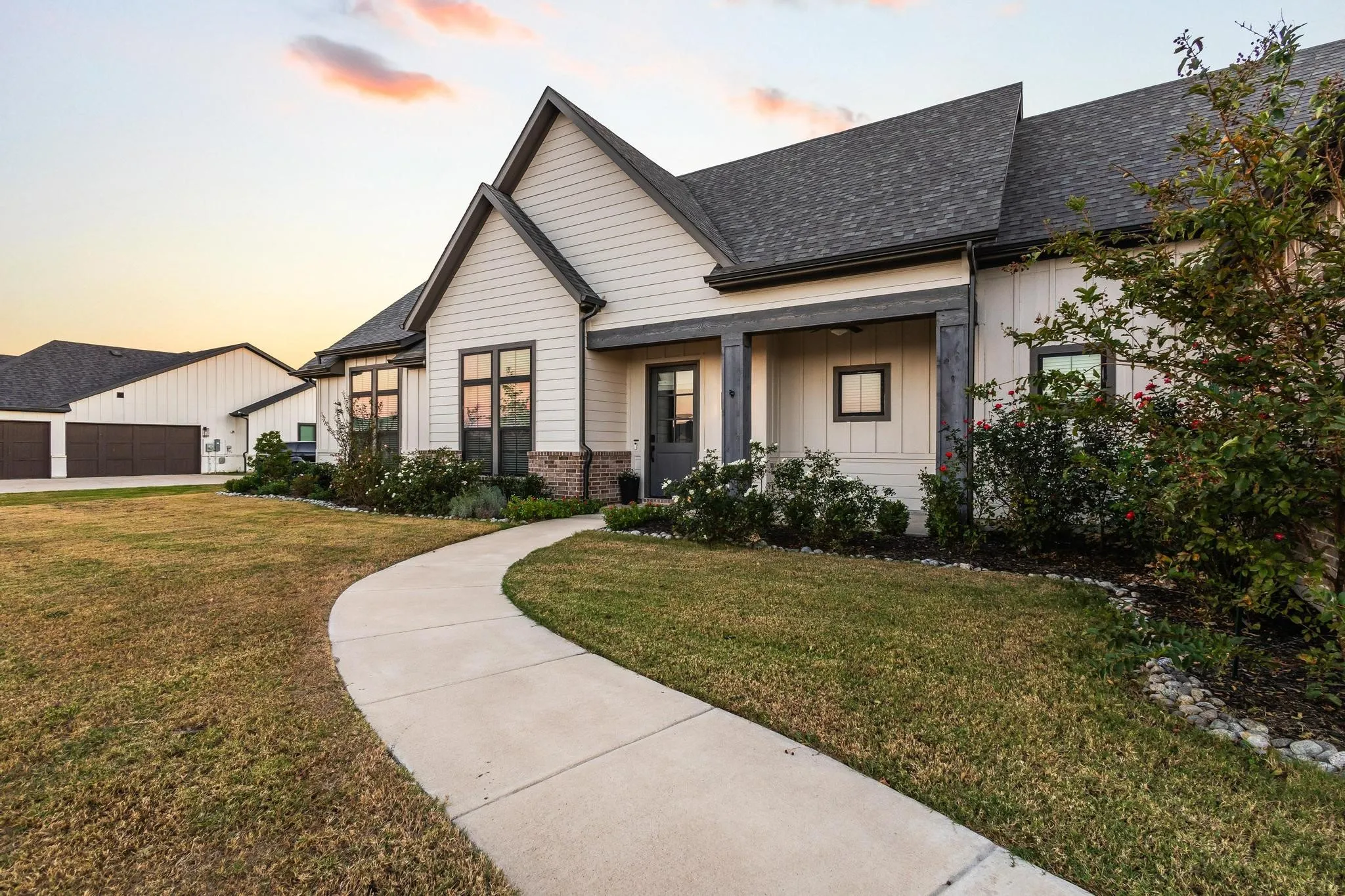 View of front of home featuring a yard, a shingled roof, brick siding, and covered porch