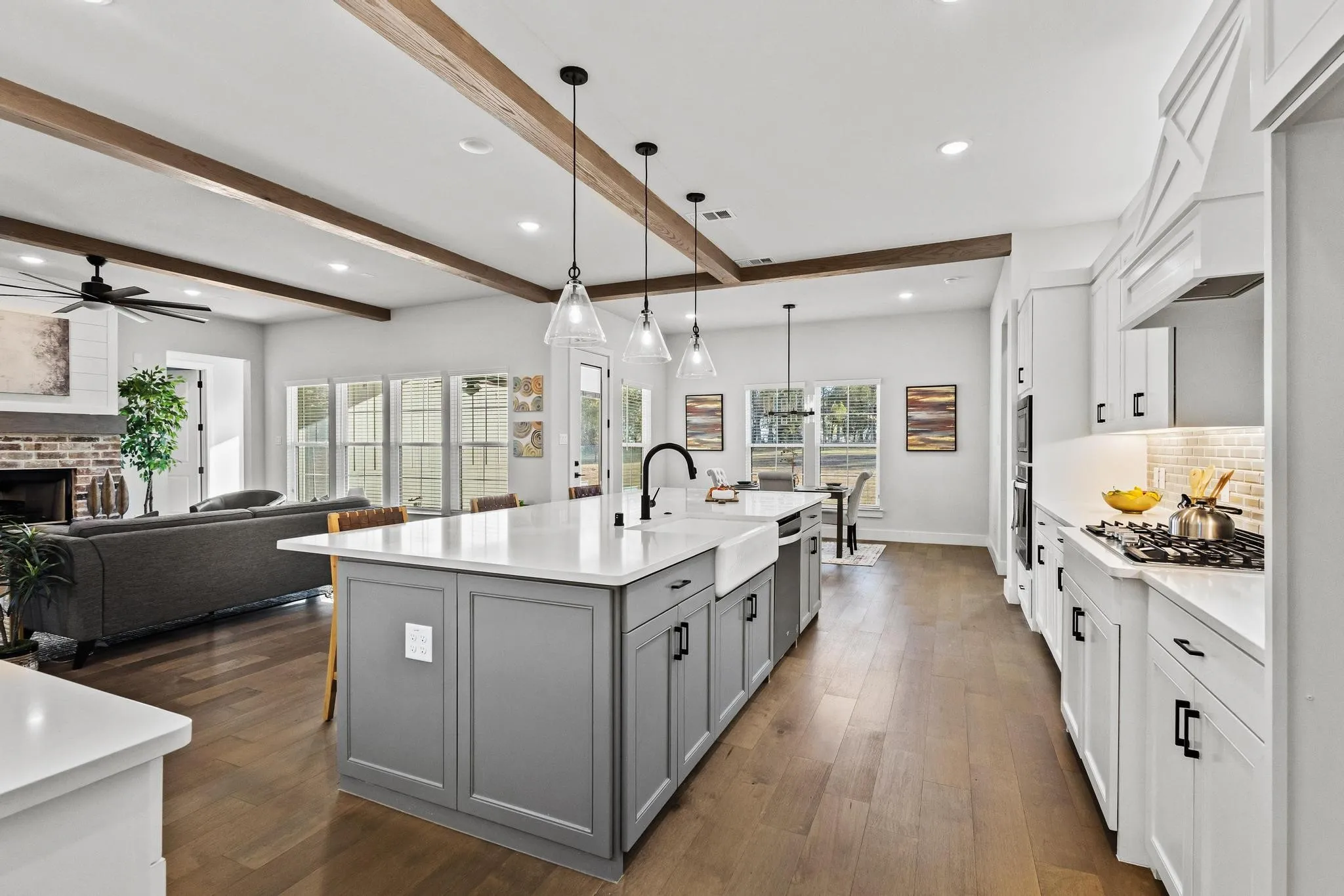 Kitchen with white cabinetry, recessed lighting, decorative light fixtures, a large island, gas stove, and backsplash