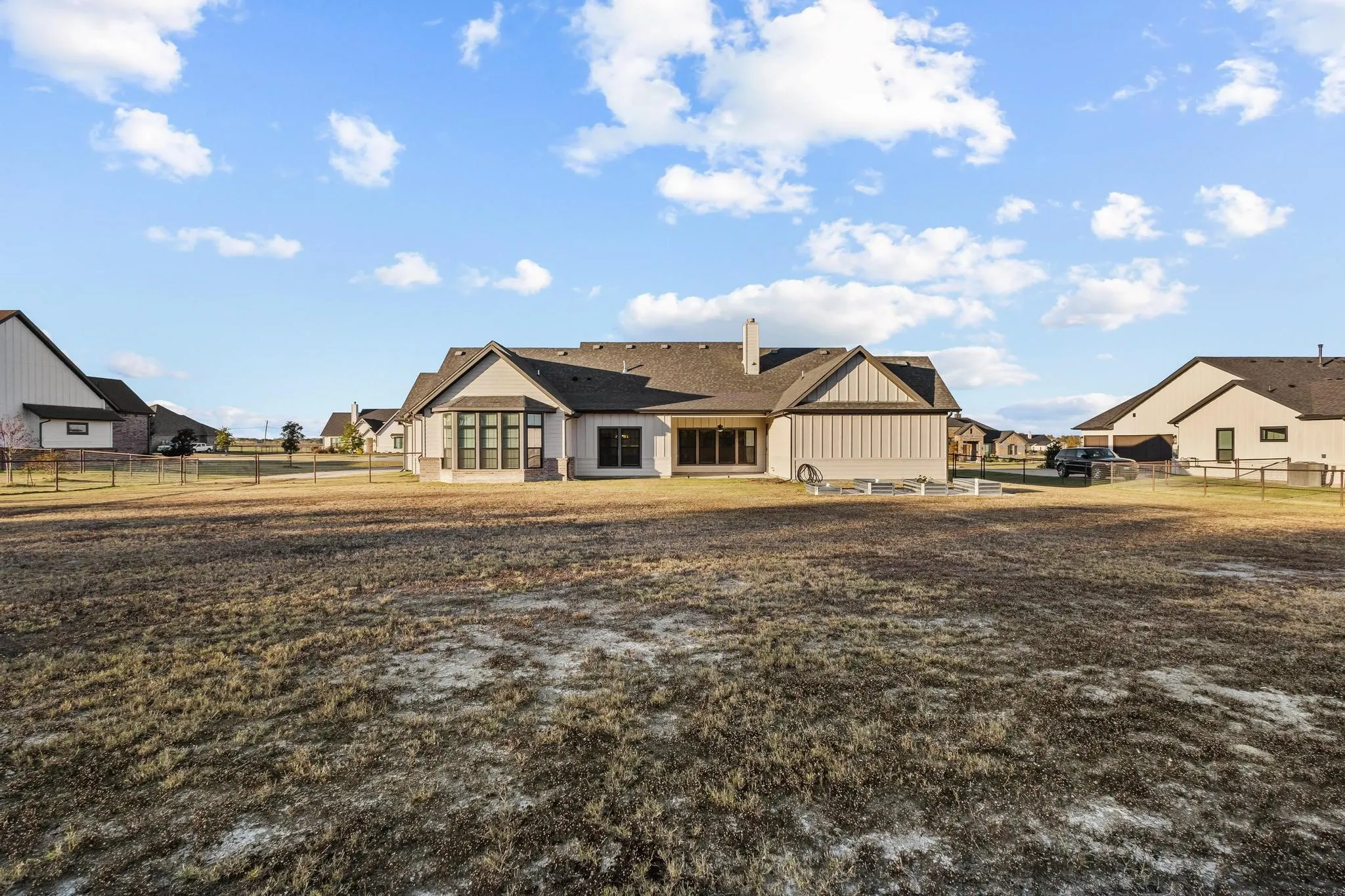 View of front of property with a fenced backyard, a chimney, board and batten siding, and a patio area