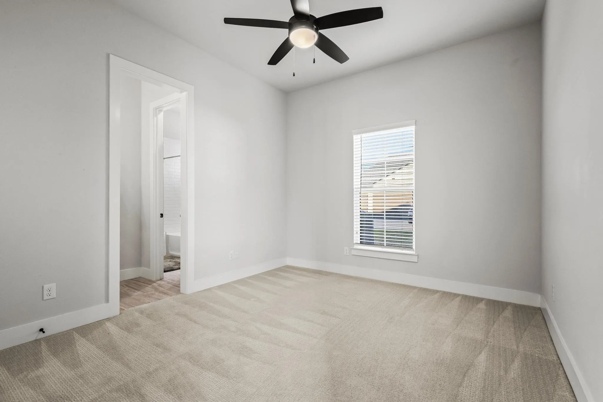 Empty bedroom with light carpet and ceiling fan