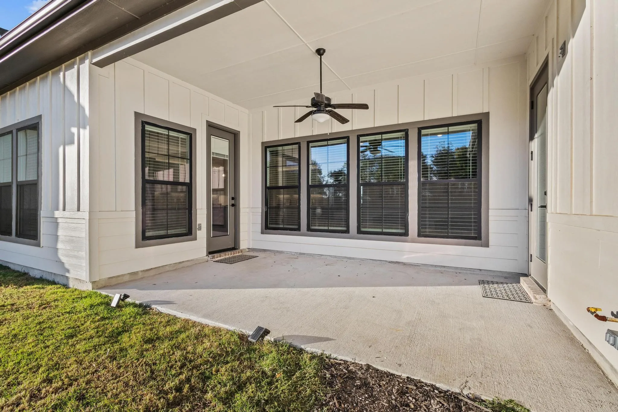 Covered Patio with ceiling fan, a patio area, and board and batten siding