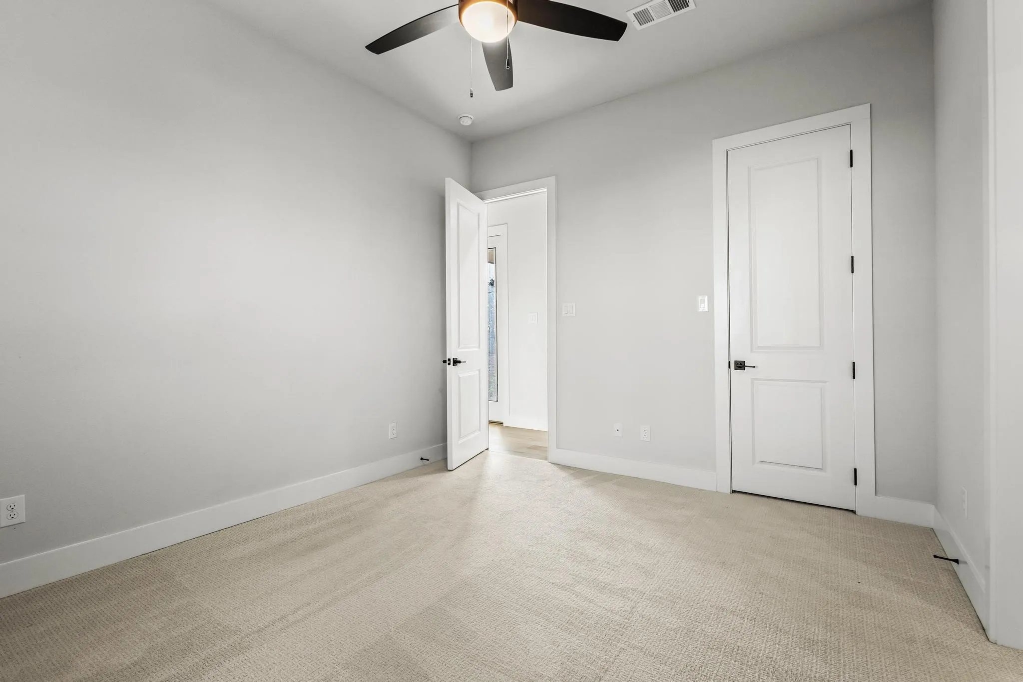 Unfurnished bedroom with light colored carpet and ceiling fan