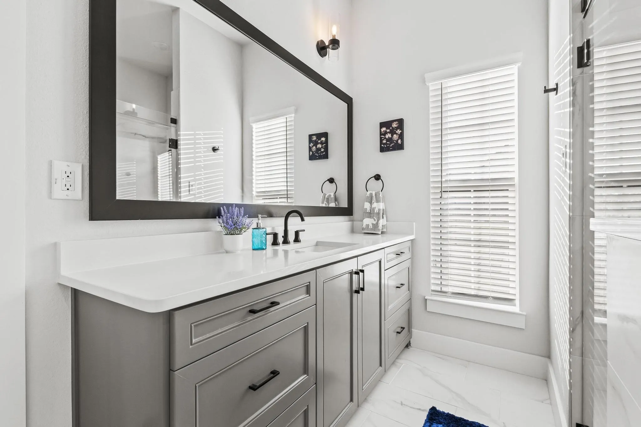 Bathroom featuring vanity and light marble finish floors. Large walk in shower in center