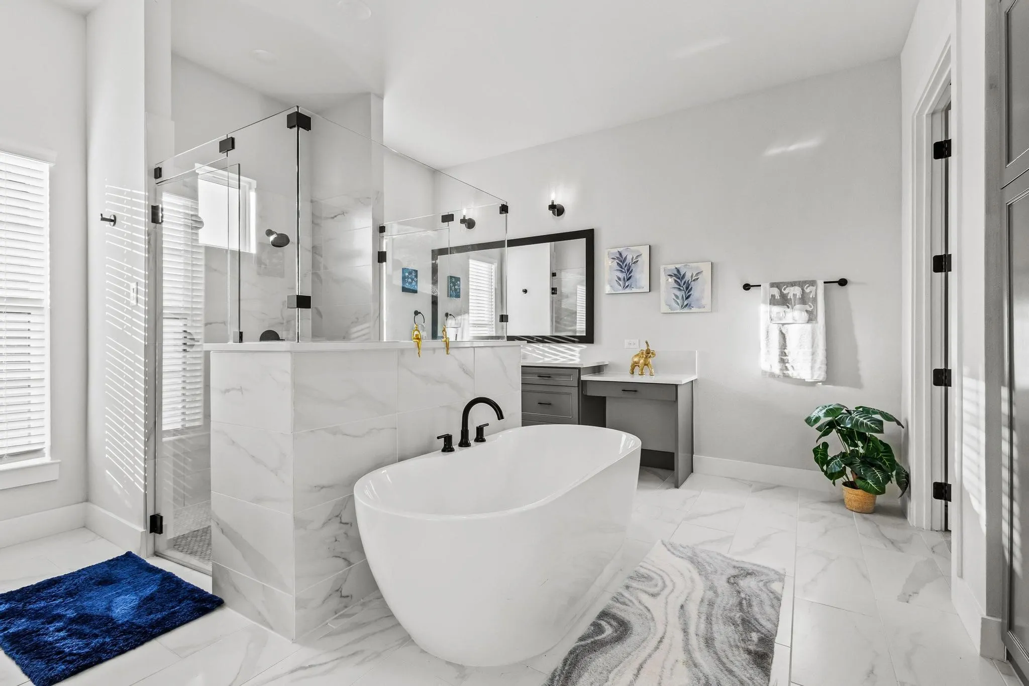 Full bath with a freestanding tub, healthy amount of natural light, vanites, and a marble finish shower