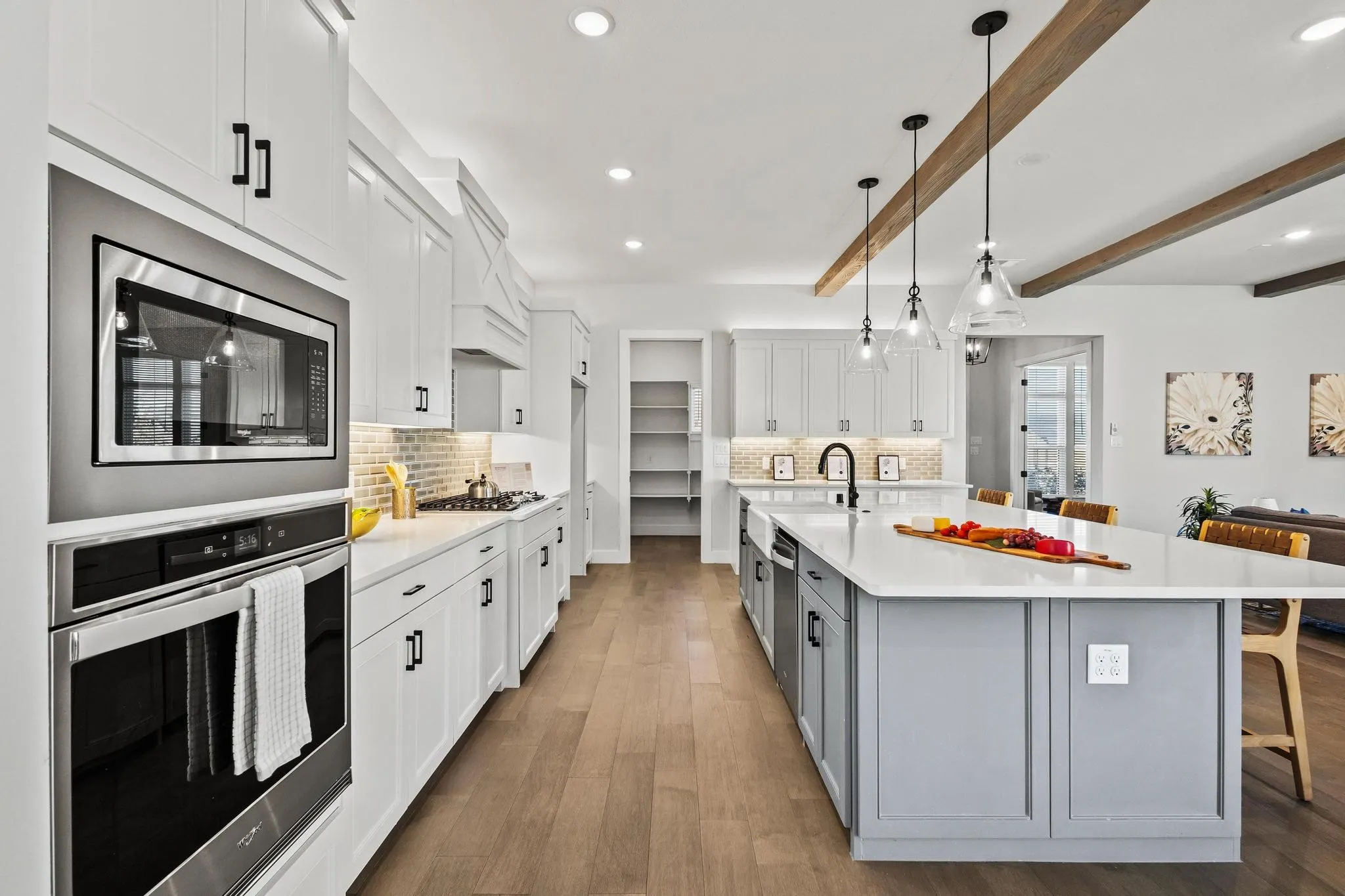 Kitchen featuring white cabinetry, stainless steel appliances, beam ceiling, a kitchen bar, and tasteful backsplash