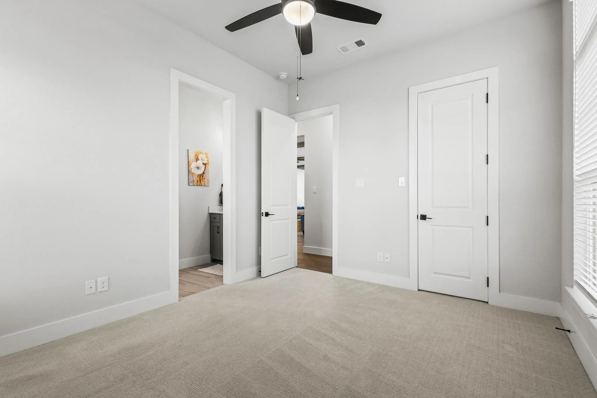 Unfurnished bedroom featuring light colored carpet, a ceiling fan, and ensuite bathroom