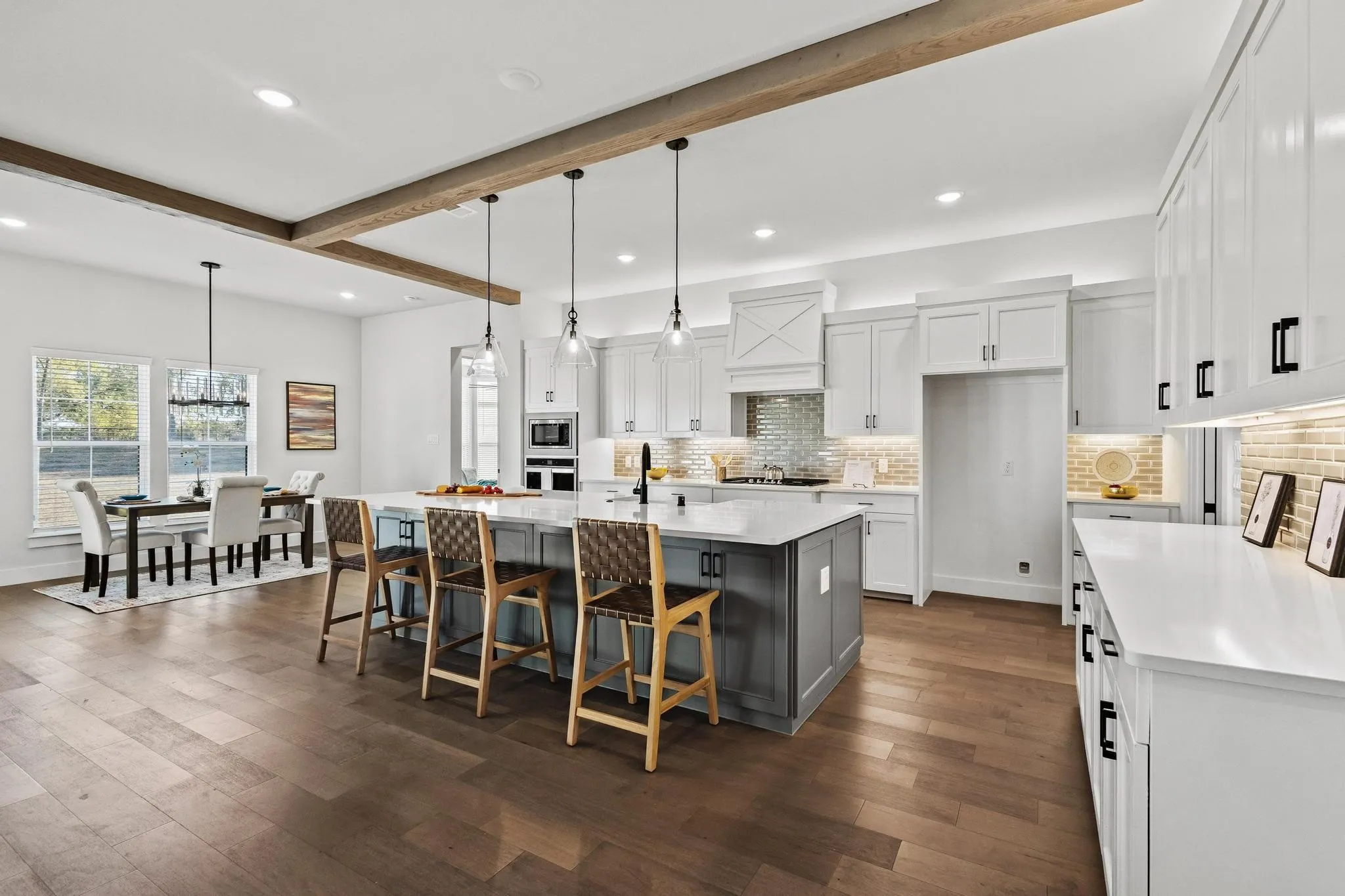 Kitchen featuring beamed ceiling, white cabinets, recessed lighting, hanging light fixtures, and a kitchen bar - many cabinets