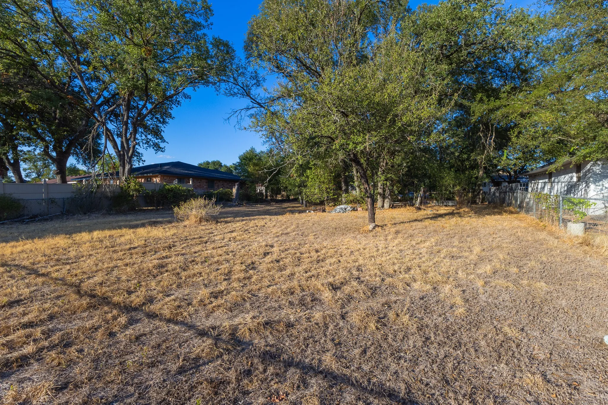 Expansive outdoor area with mature trees and a chain link fence