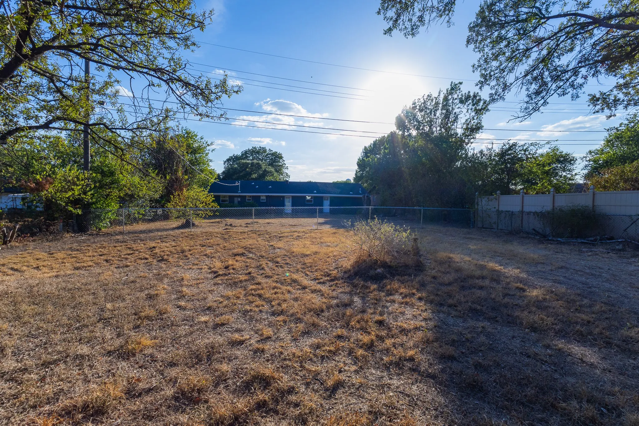 Expansive rear yard with a chain-link fence and a concrete wall perimeter