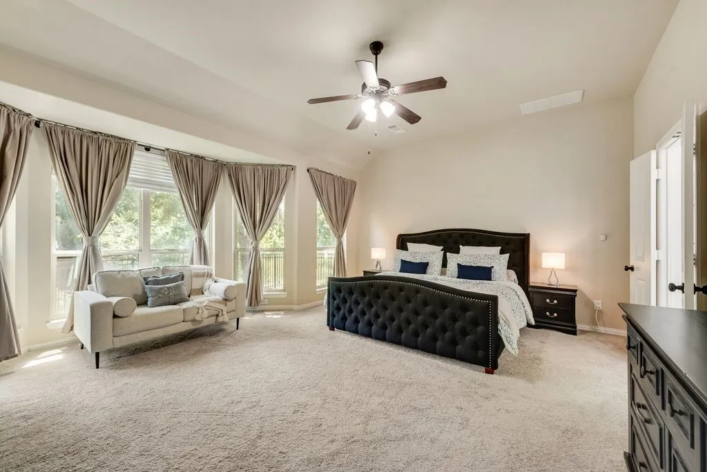 Vaulted ceiling with a ceiling fan, bay window with multiple paneled windows, and neutral carpeting
