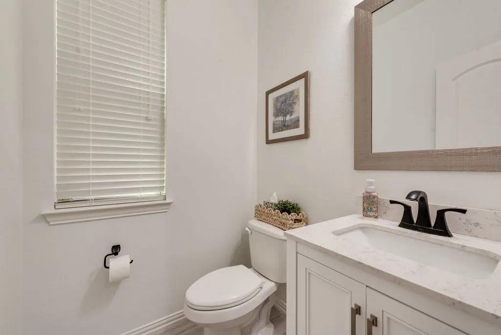 White shaker-style vanity with a light-toned countertop, rectangular undermount sink, and black faucet