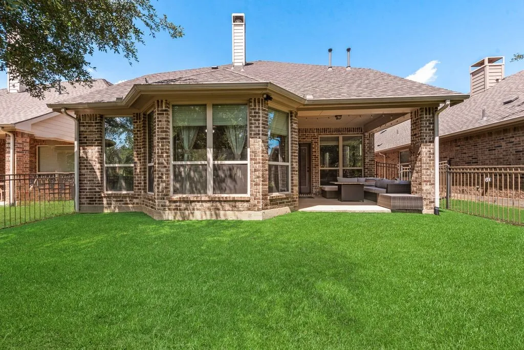 Brick exterior, covered patio, expansive backyard, multiple windows, and a privacy fence