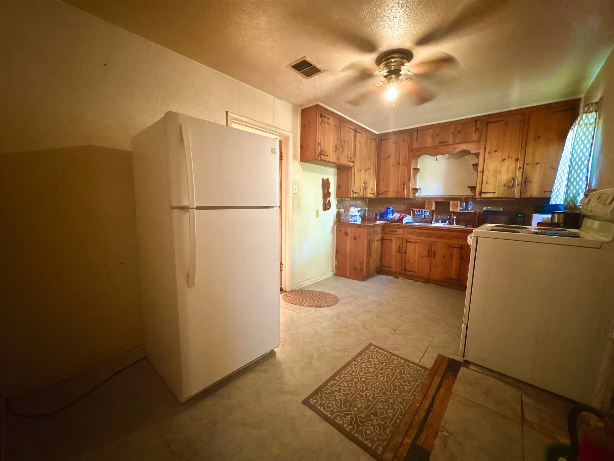 Kitchen featuring wood cabinetry, ceiling fan with light fixture, and tile-finish flooring