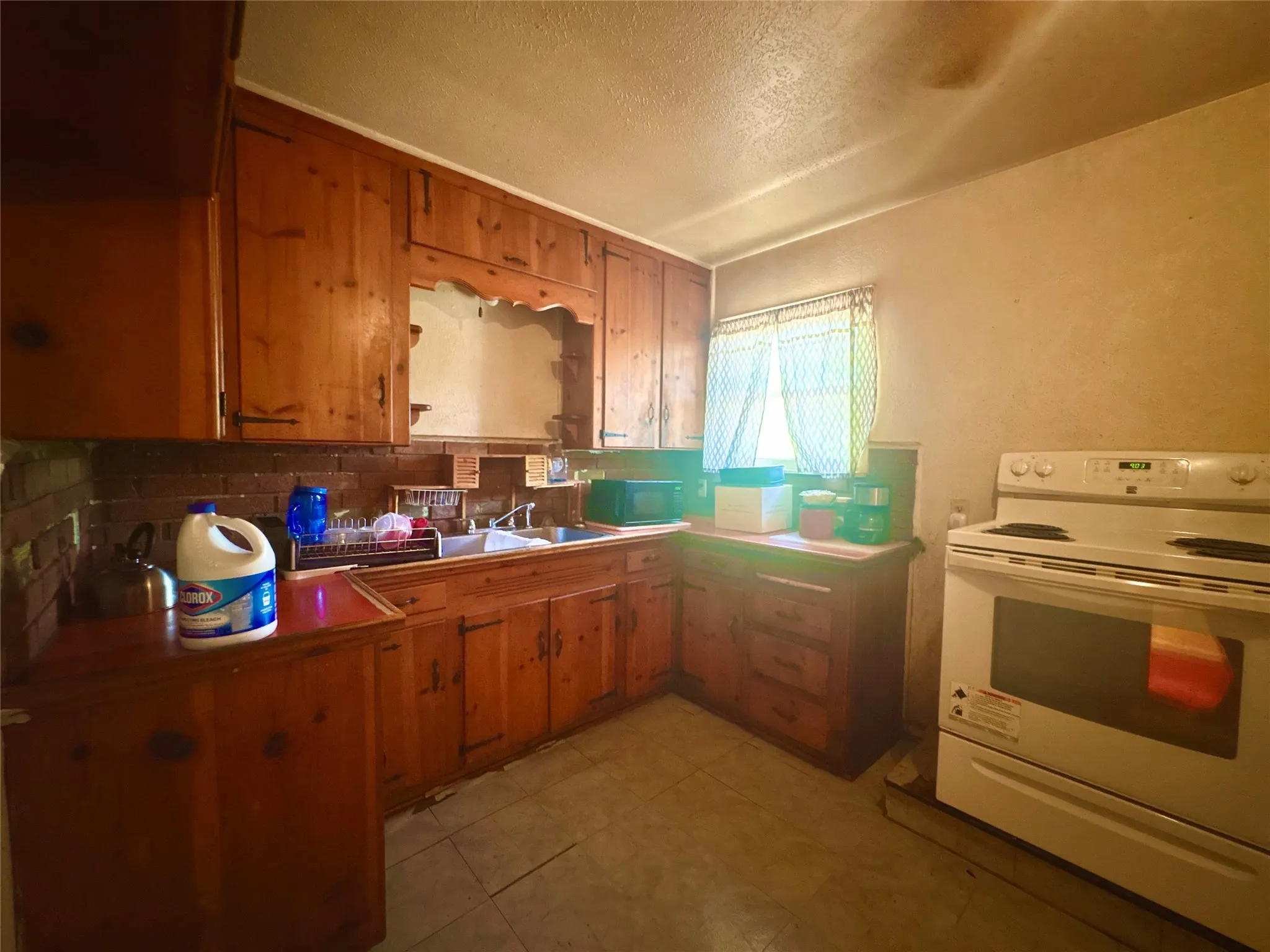 Kitchen featuring wood cabinetry, a stainless steel sink, and tile flooring