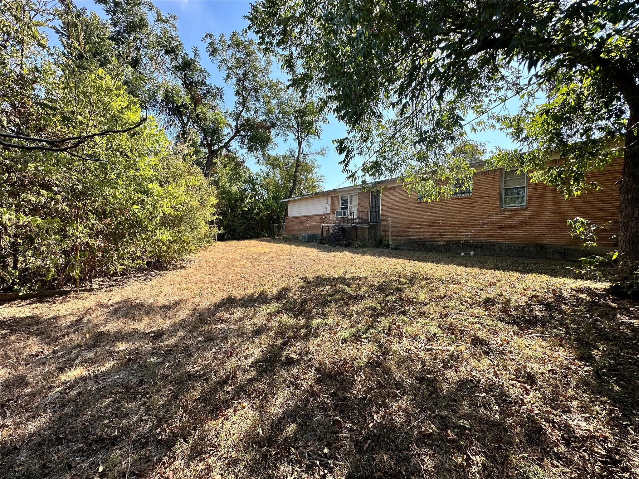 Brick exterior with a partial rear deck, surrounded by mature trees and natural vegetation