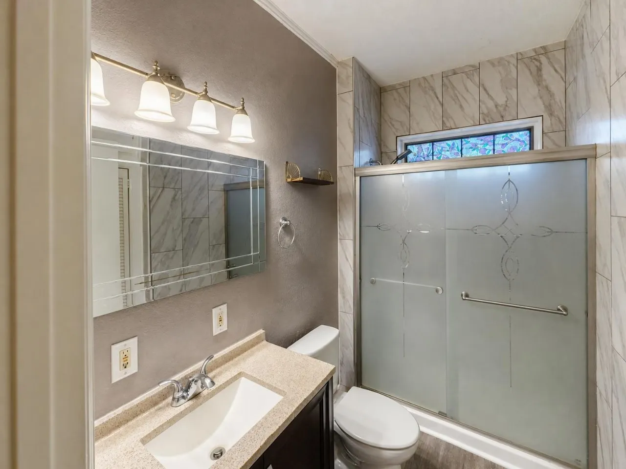 Vanity with stone-finish countertop, decorative mirror, and four-light fixture