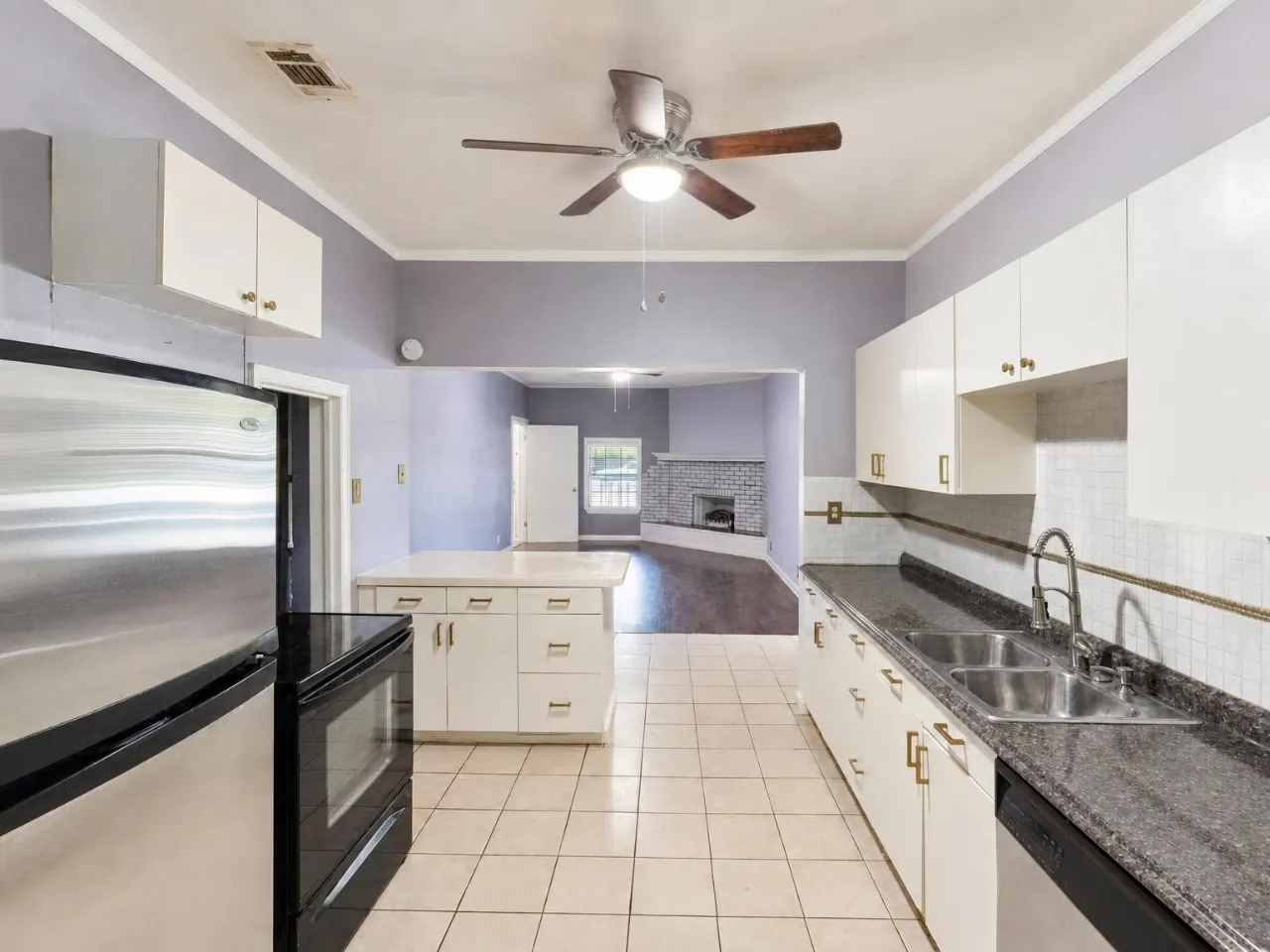 Kitchen featuring white cabinetry, dark granite-style countertops, stainless steel appliances, and tile flooring